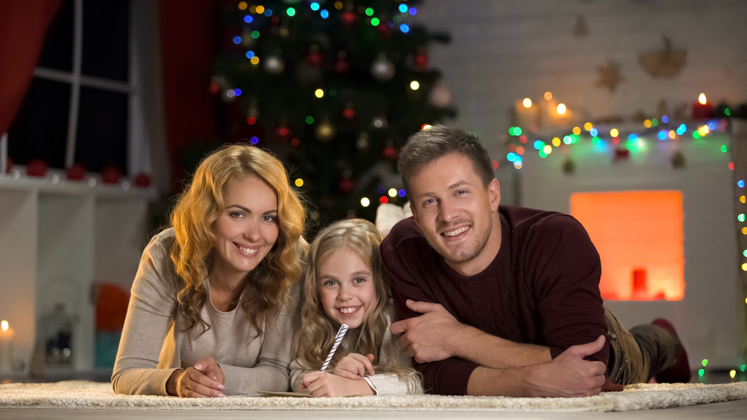 Young family smiling at camera, composing letter to Santa, belief in fairy-tale