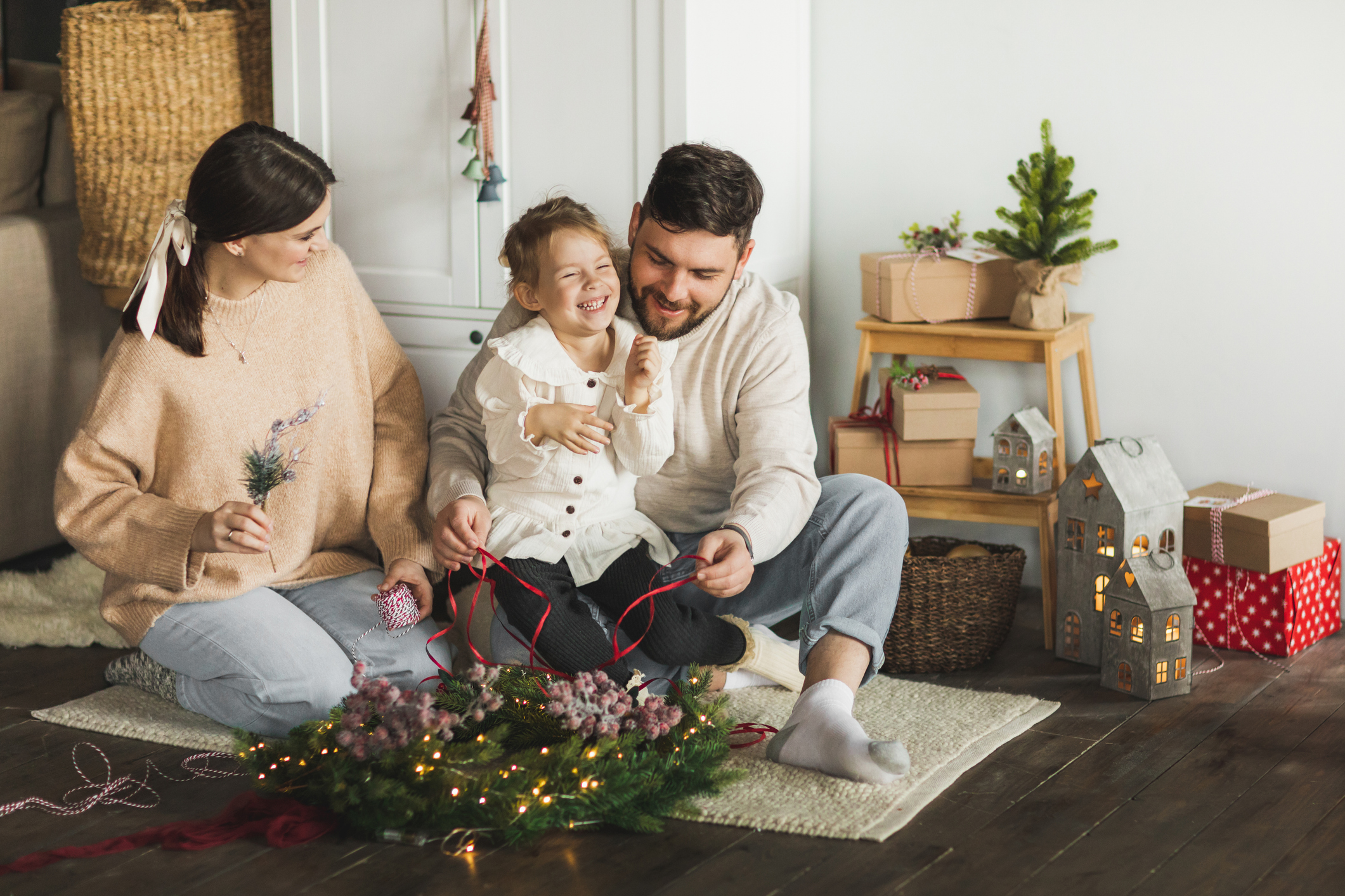 Family making Christmas wreath at cozy home.