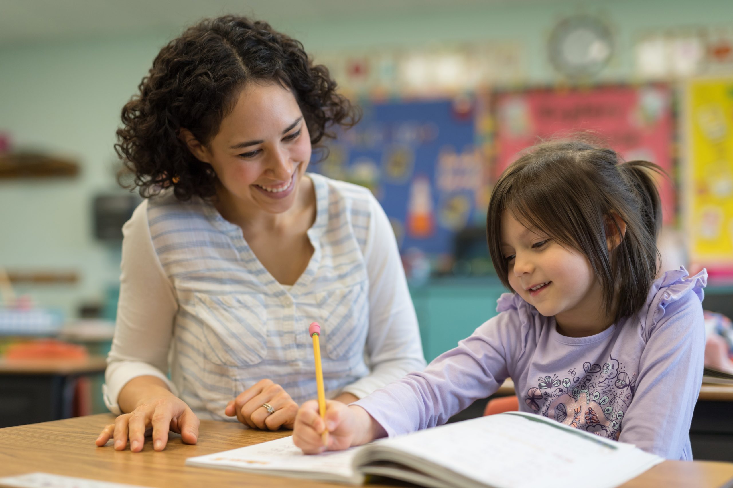 First grade girl talking with her teacher in the classroom